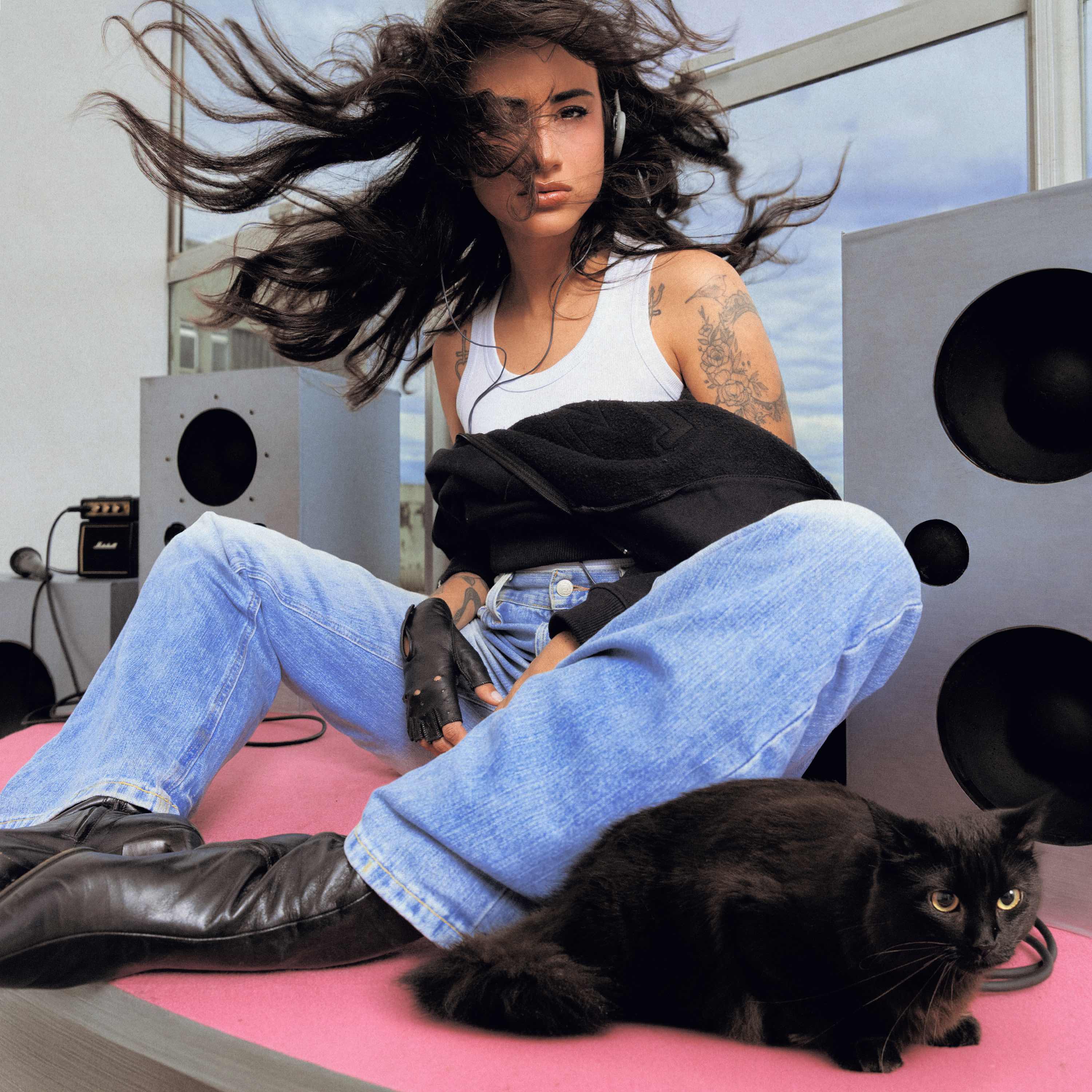 Capa da mixtape PUT@RIA & POE$IA: DAY LIMNS de fones e regata branca, sentada entre caixas de som com um gato preto ao lado